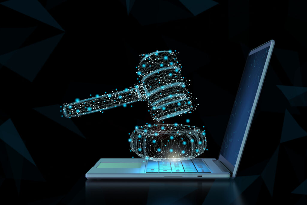 A digital gavel made of glowing blue dots appears above a laptop keyboard, symbolizing online law, cybersecurity, or digital justice, against a dark geometric background.